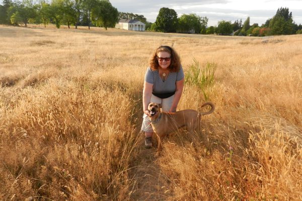 Owner sitting in a field of golden grass with a small young dog